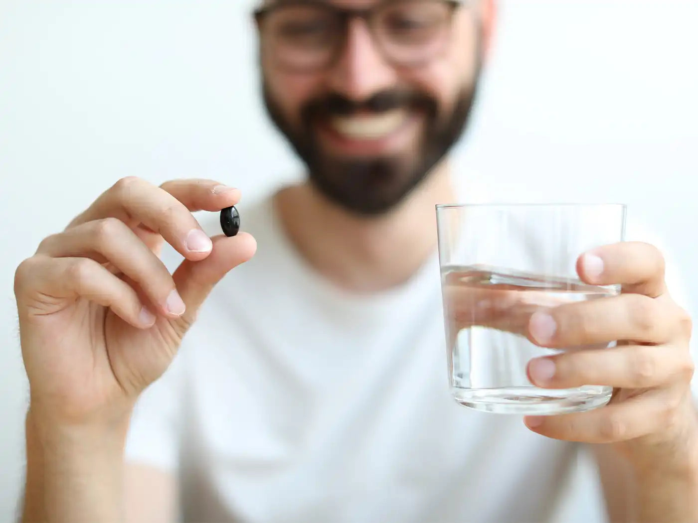 Mann hält Softgel und ein glas wasser in den Händen 